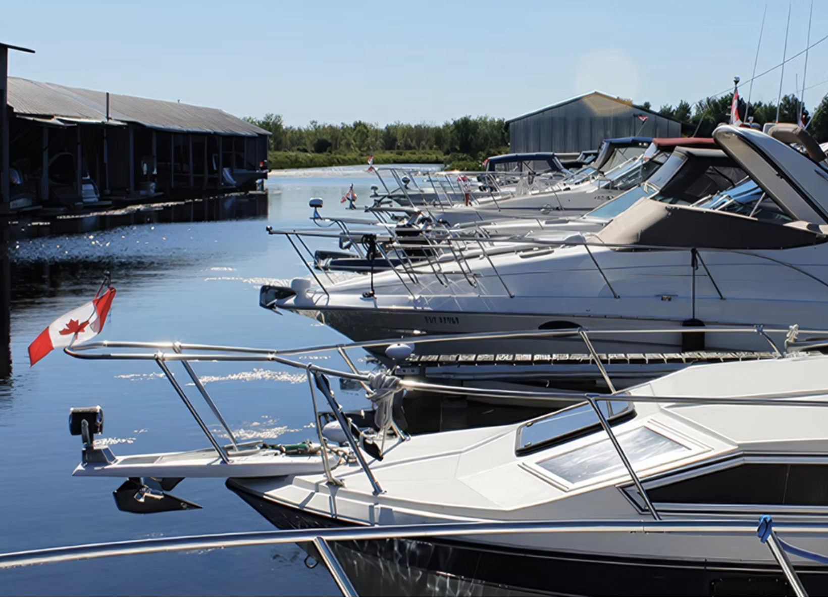 a row of boats tucked into slips on the calm water of Everglades Marina on a clear summer day. 