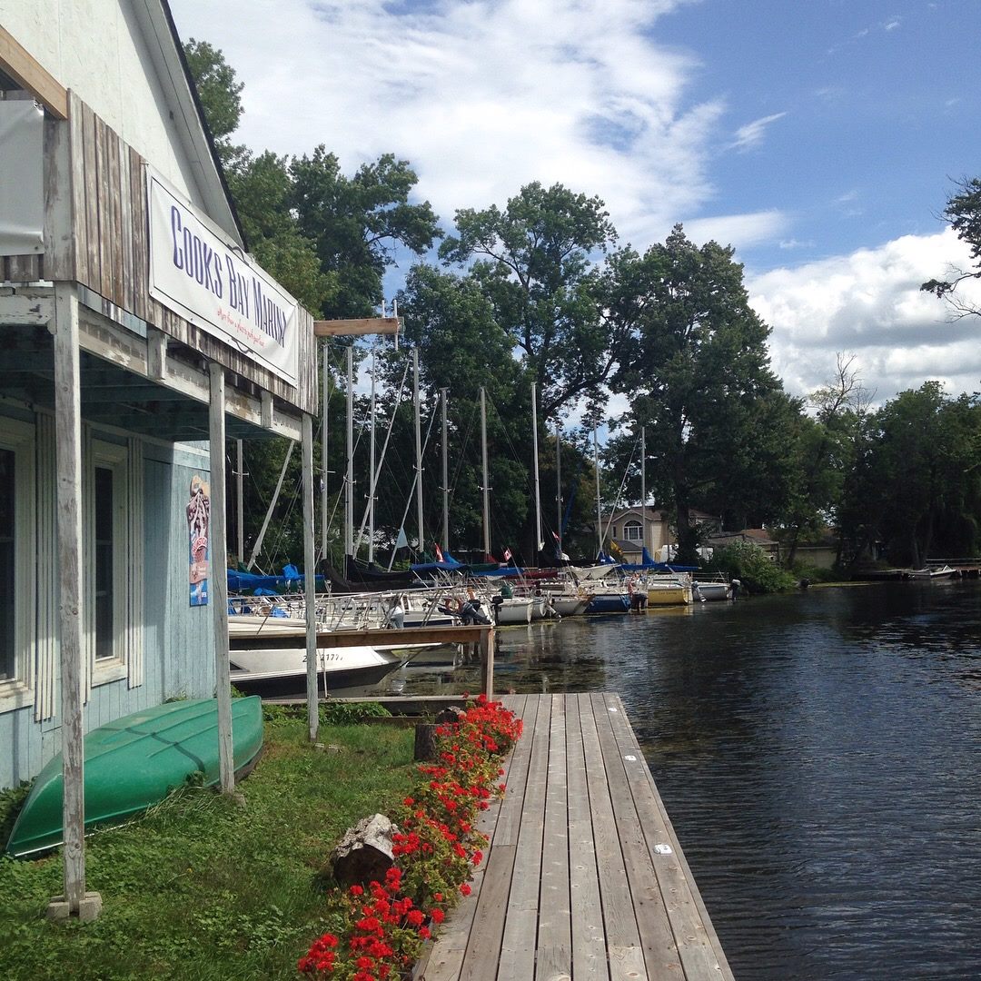 a wooden marina store along a flower-lined wooden boardwalk skirts the calm water of the quiet Cook's Bay Marina.