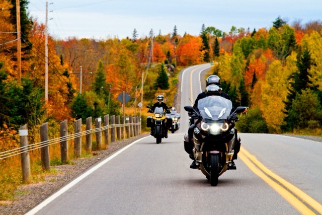 Two riders on a straight road in fall 