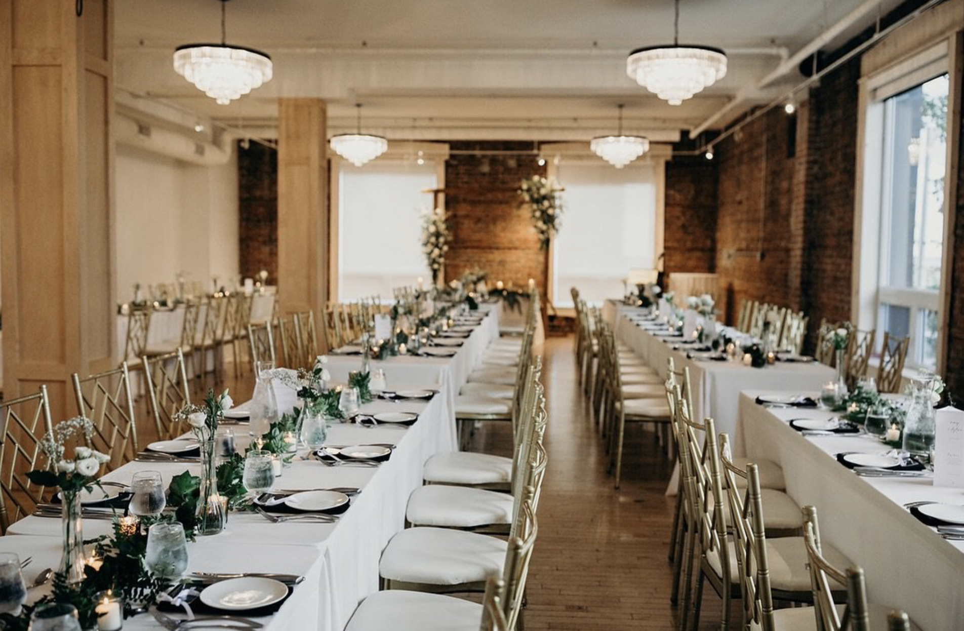 tables set with white linens, china and flowers under soft chandelier lighting at The Chanterelle on Park. 