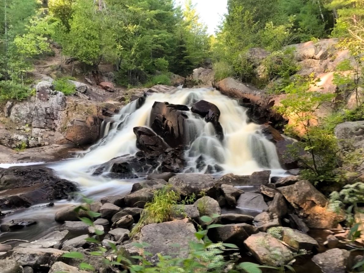 Duchesnay Falls near North Bay, a soft cascade of white water tumbling down a rock face in a lush green woods.