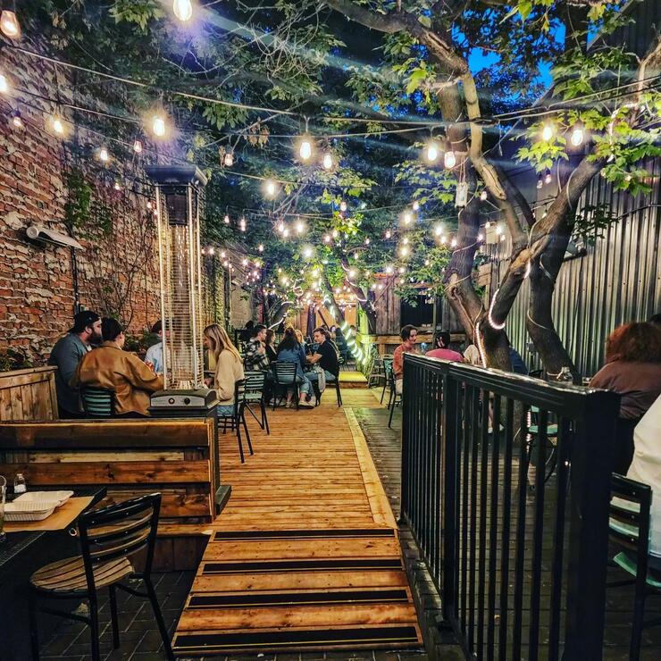 Laughing Buddha patrons dine on the intimate outdoor patio lit up with string lights in the summer night. 