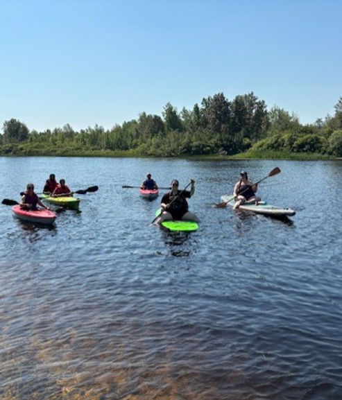 A group of paddlers wave from their kayaks on the sparkling river near Timmins on a clear summer day. 