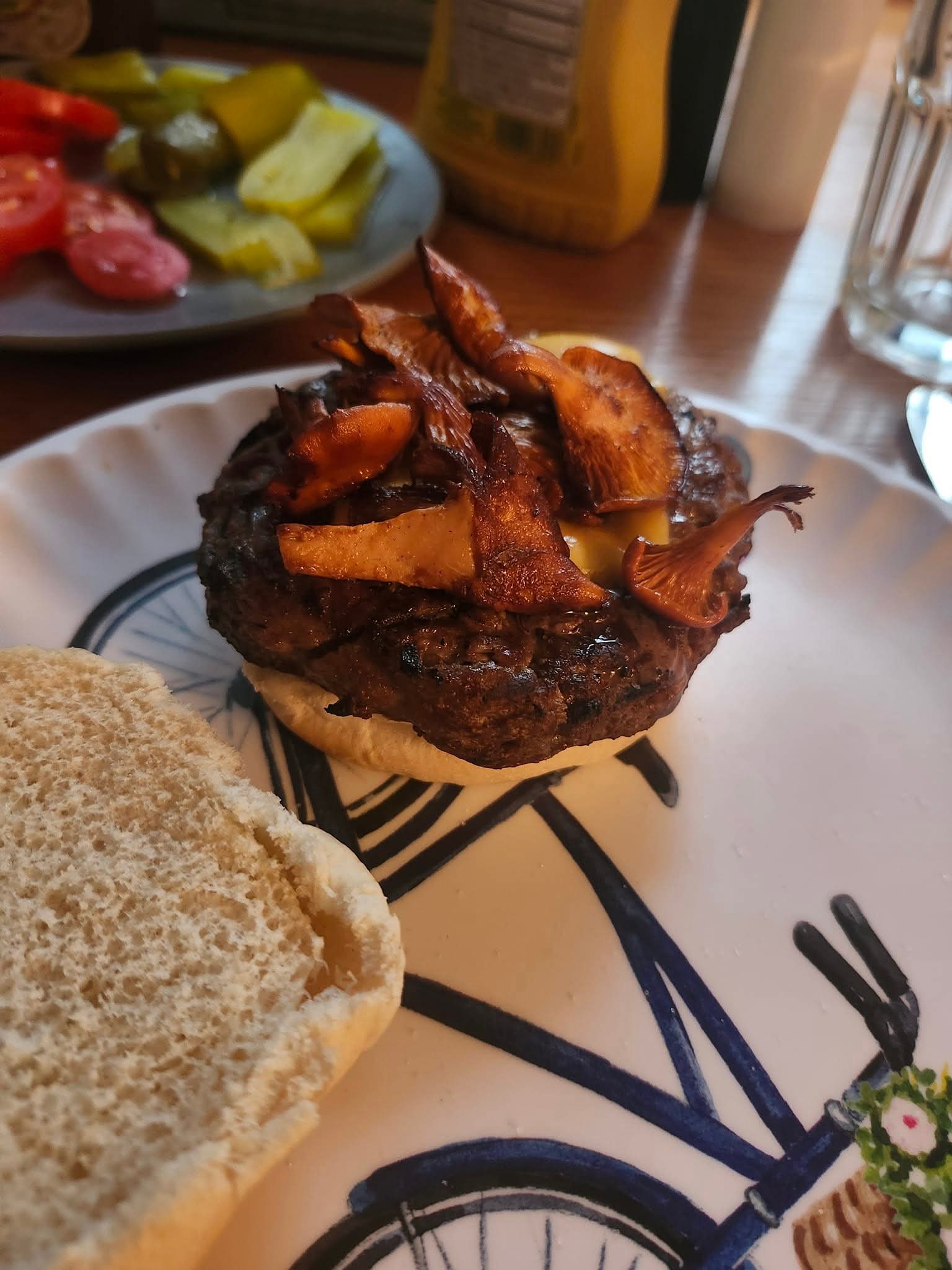 a freshly grilled hamburger topped with halved chanterelle mushrooms 