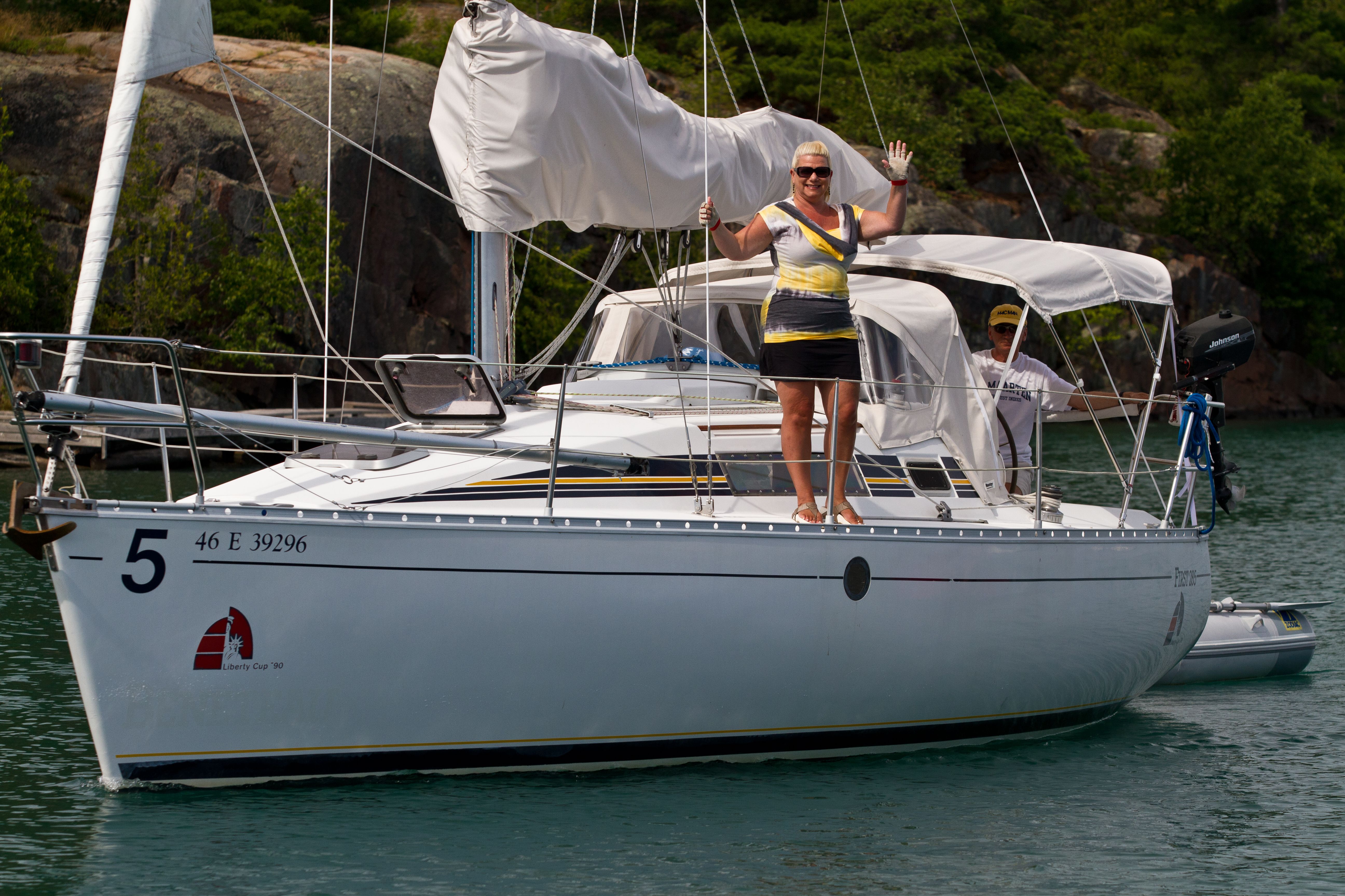 A woman and man wave from their boat on a breezy summer day near Killarney. 