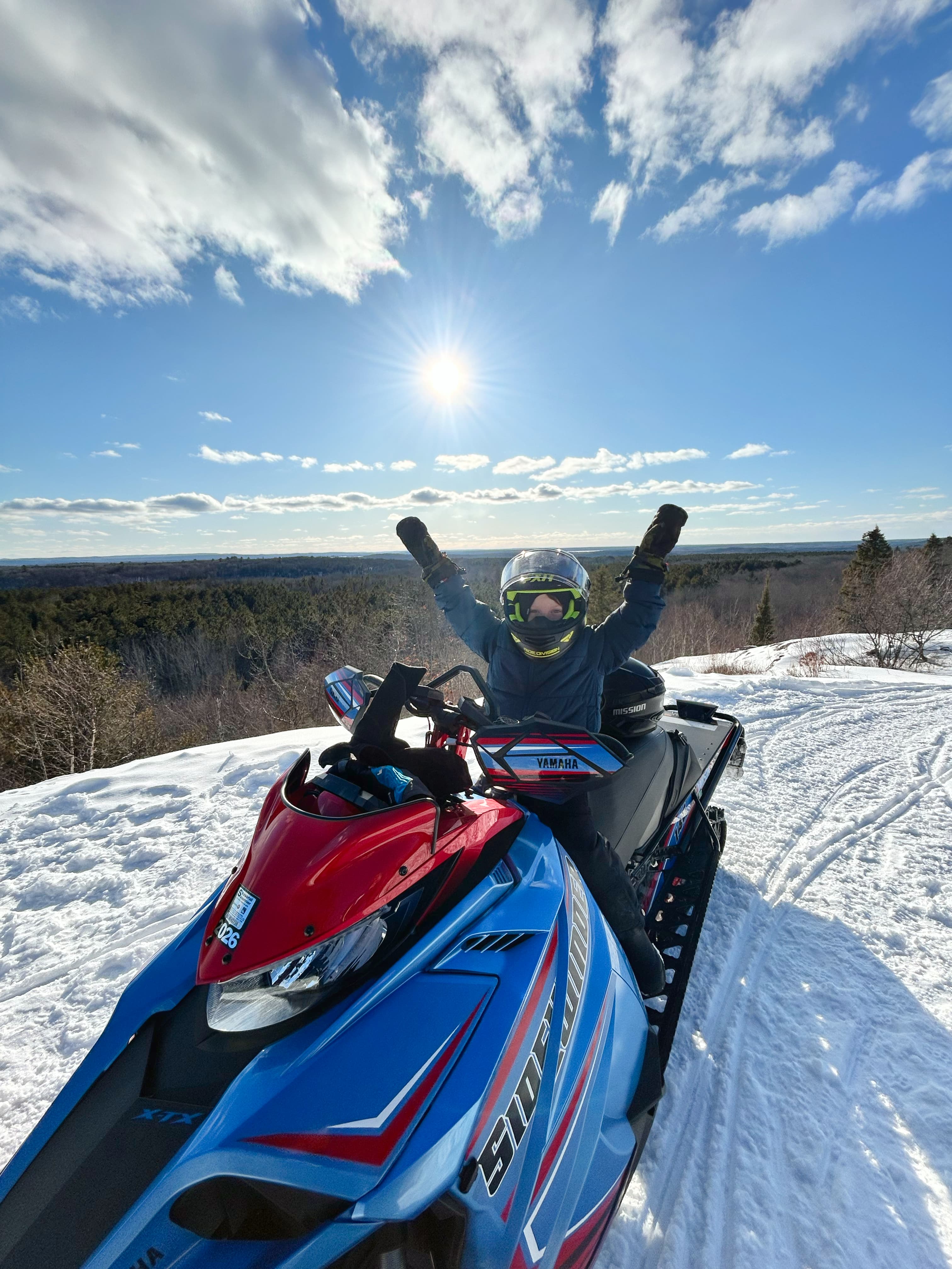 kid with arms raised on snowmobile on mountain