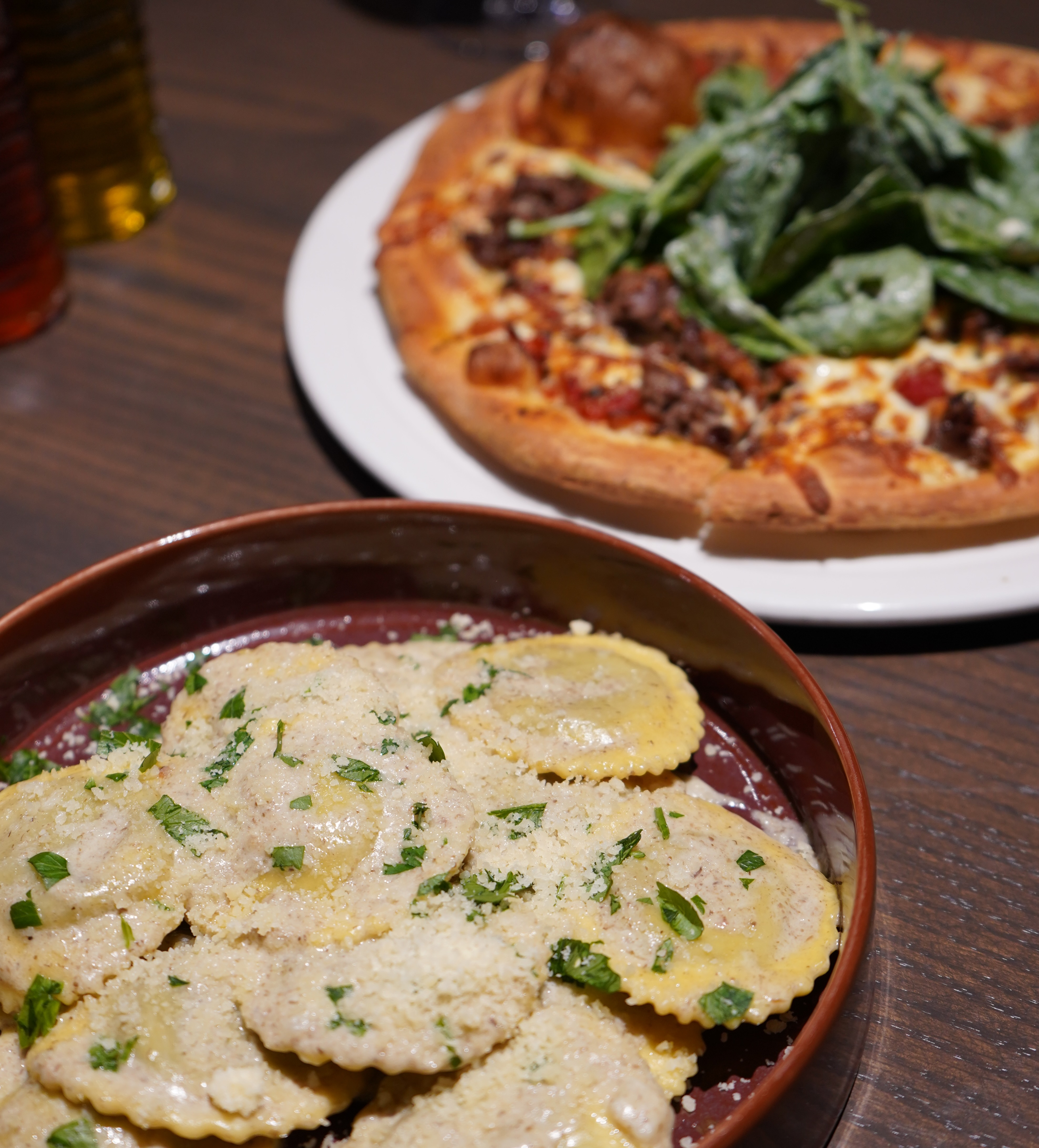 dishes of homemade ravioli and pizza garnished with fresh herbs from Mazi.