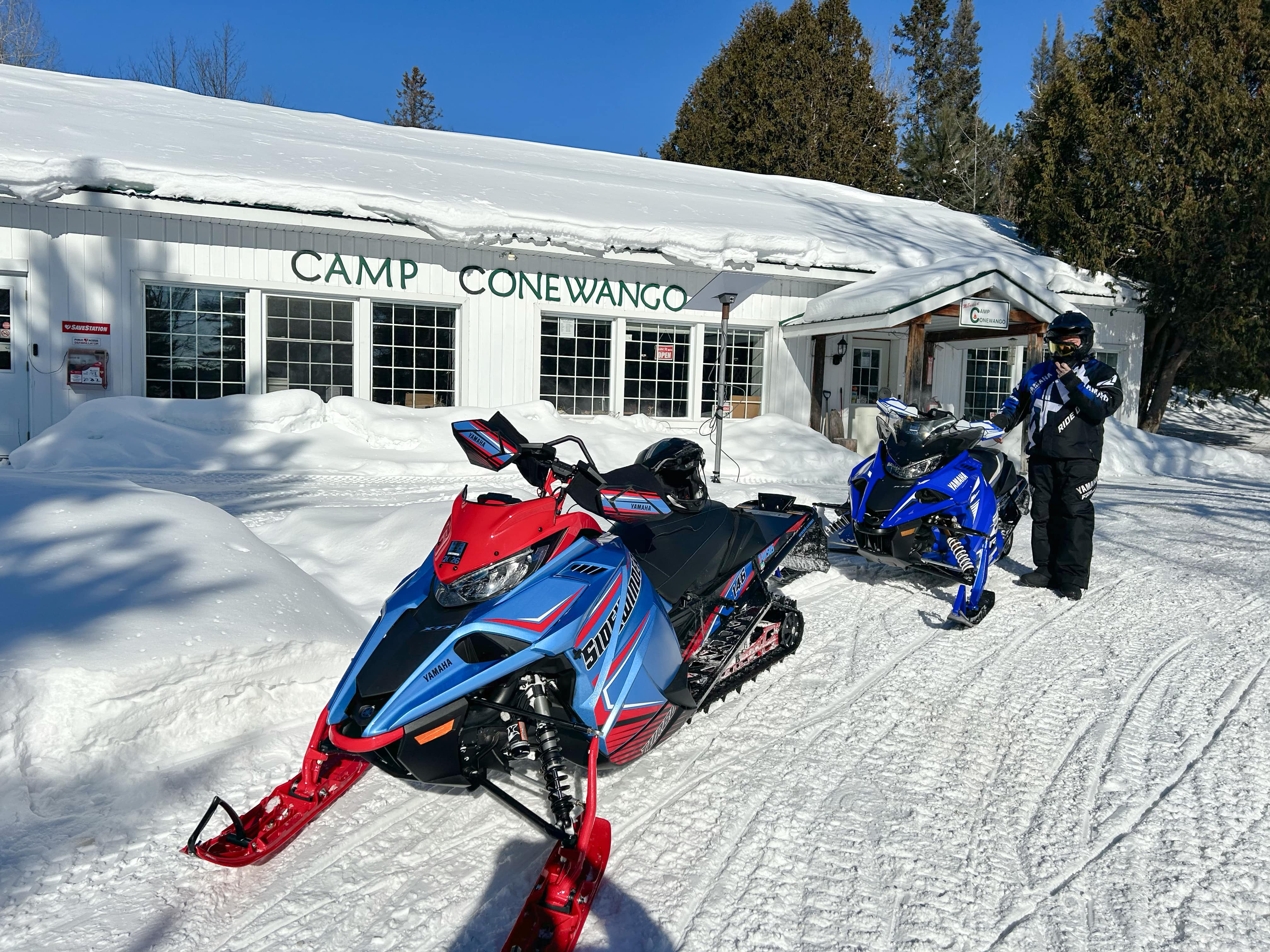 snowmobiler and sleds in front of building