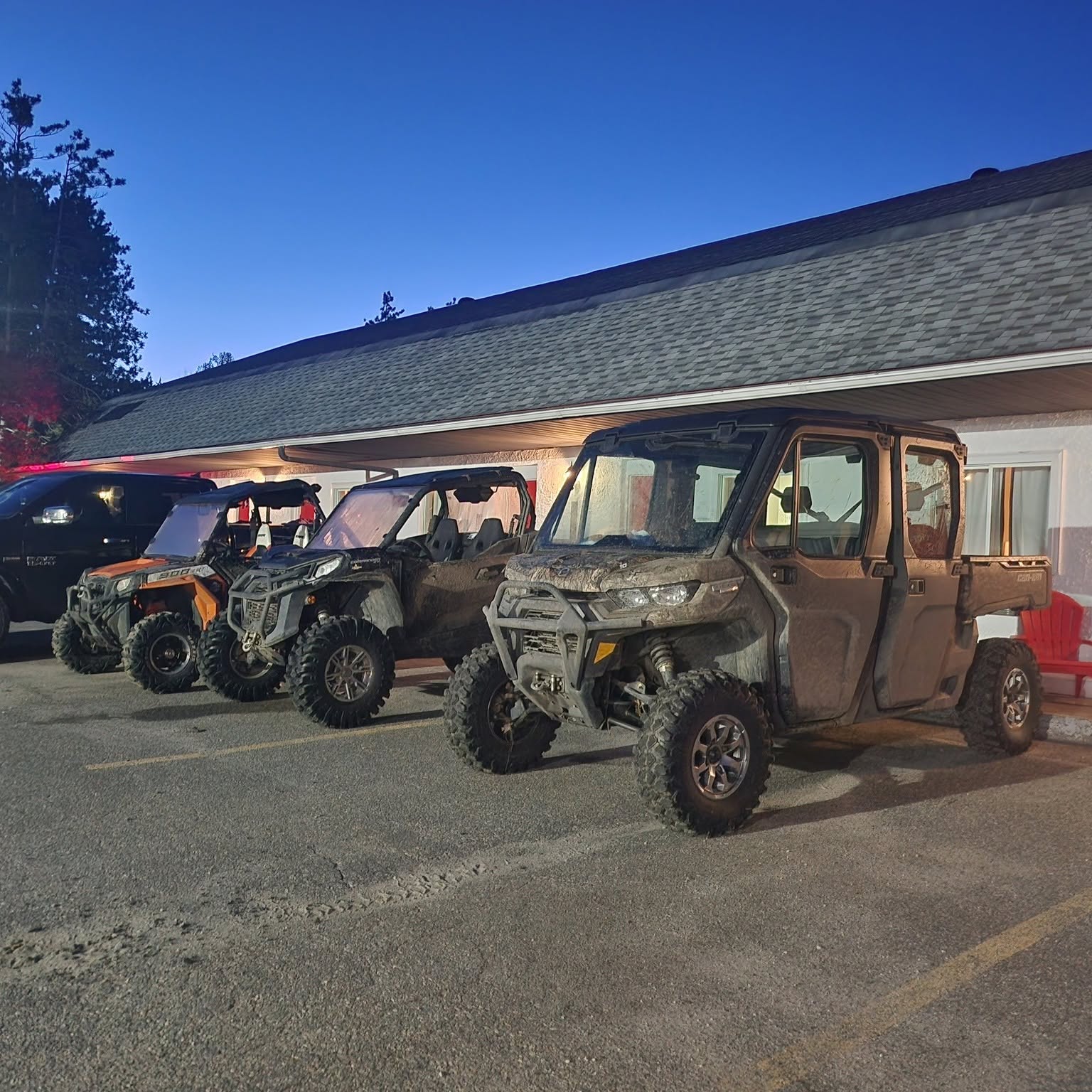 a line of UTVs parked outside of Jolly Roger in Parry Sound at dusk in the summer.