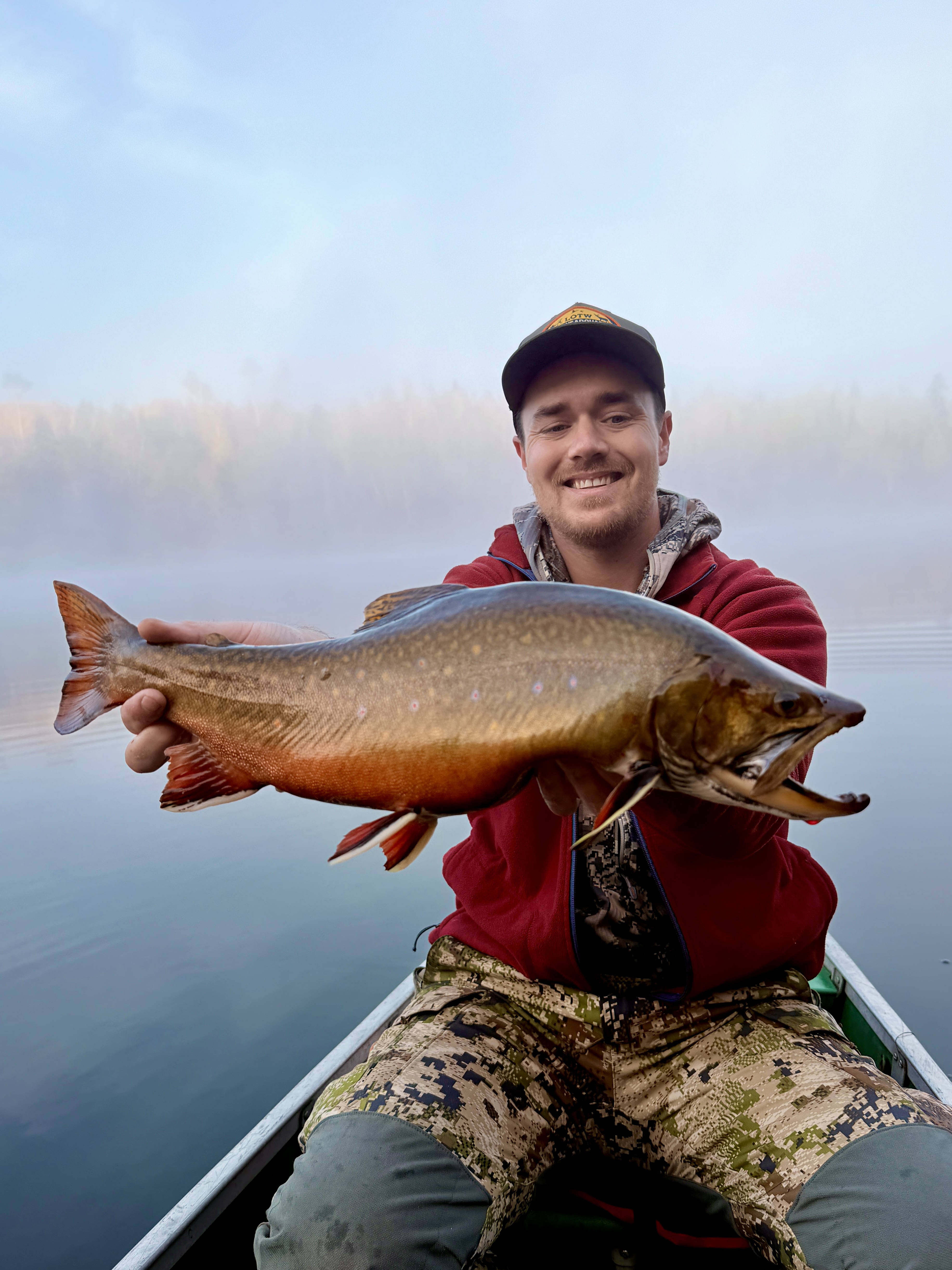 Holding an Aurora trout in the early morning in a small boat on a lake