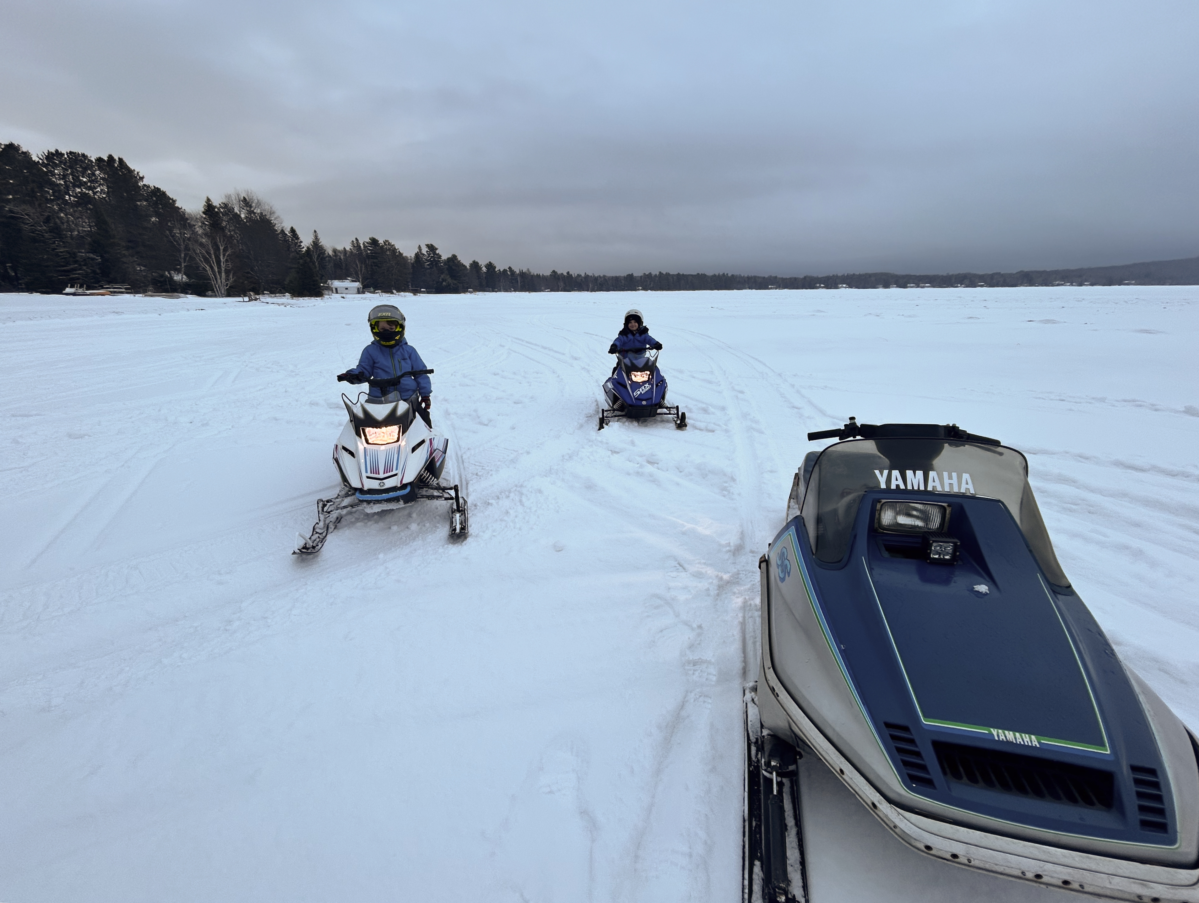 Kids on snowmobiles on frozen lake