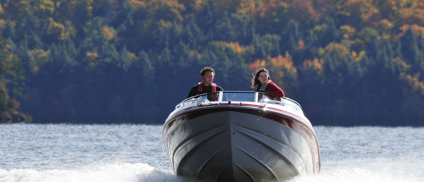 Two happy people in a motorboat whipping along a lake in September.