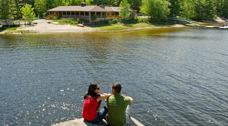 Couple sitting on a rock looking at a lodge across a river
