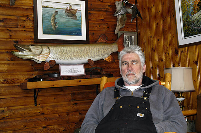 Vermilion Bay Lodge owner Gord Bastable sits in front of a wooden replica of the biggest muskie caught in Eagle Lake â a 61-pounder Edward Walden caught in 1940.