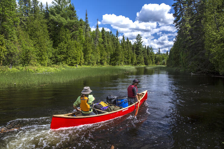 Two people paddling a red canoe. 