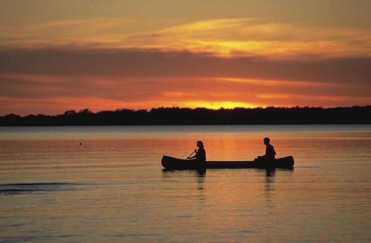 Two people paddling a canoe at sunset. 