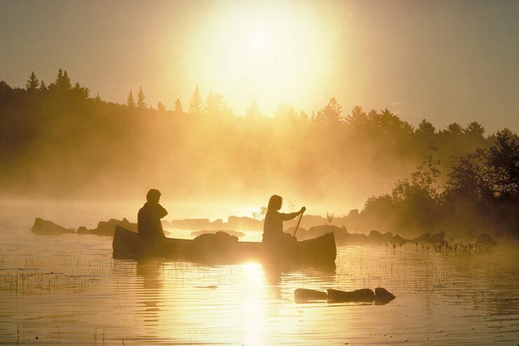 Two people paddling a canoe in the morning mist