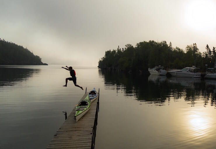 Man jumping off a dock at sunrise. 