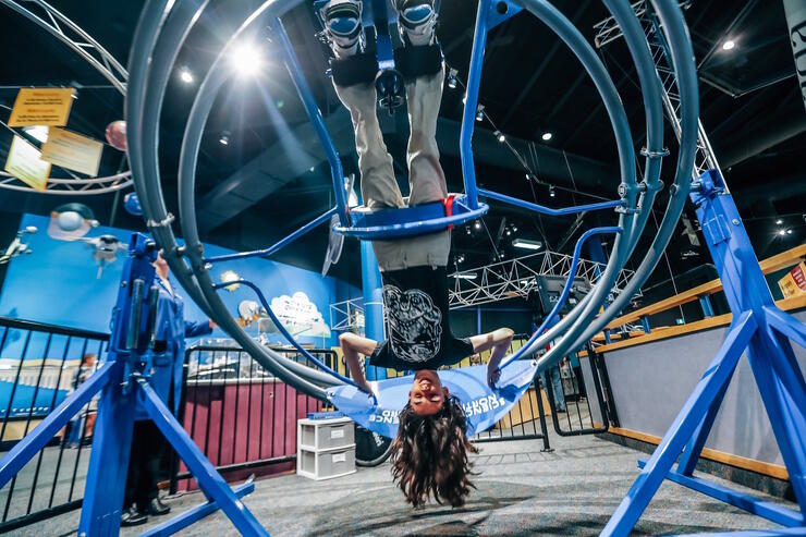A girl hanging upside down in a contraption at Science North. 