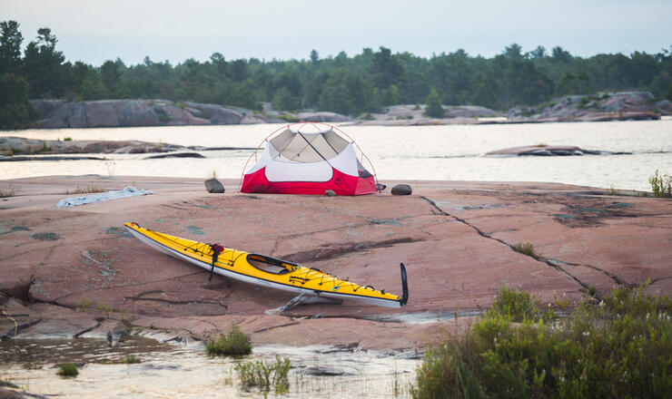 Tent and kayak on smooth rock island in Georgian Bay. 