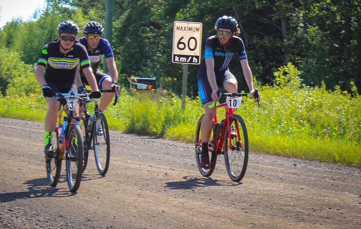 Three cyclists riding on a flat gravel road