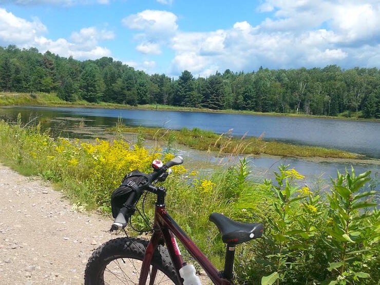 Bike on gravel road in front of pond.