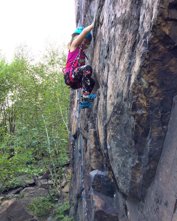 Young girl climbing a vertical rock face. 