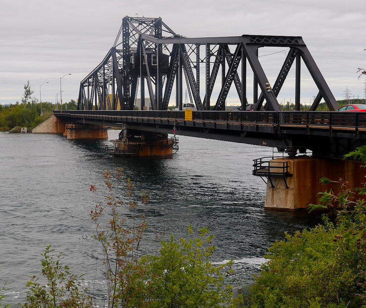 Car crossing a large metal swing bridge. 