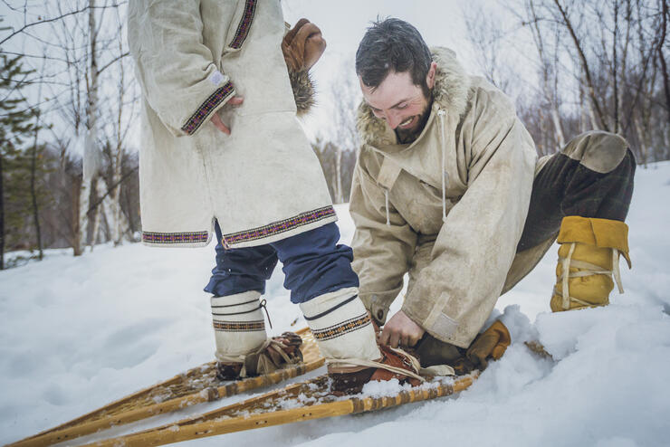Man doing up a snowshoe harness for a woman.