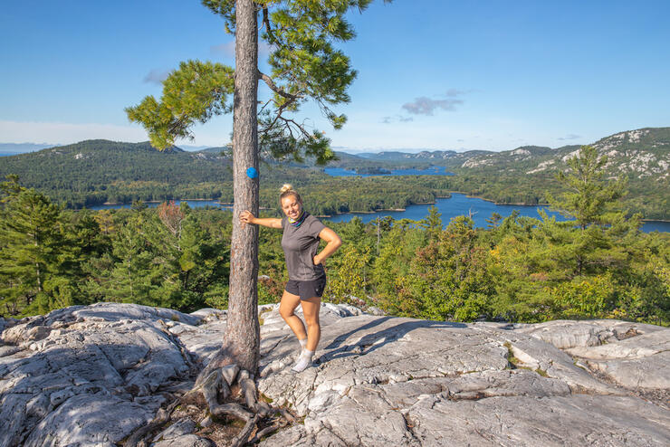 Woman standing beside a tree on a rock lookout