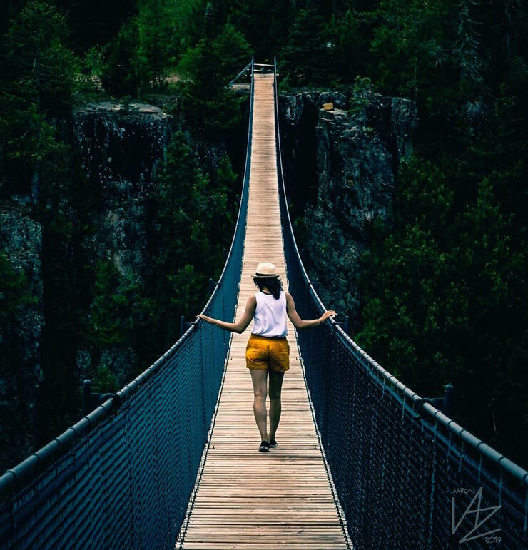 Young woman walking along a suspension bridge. 