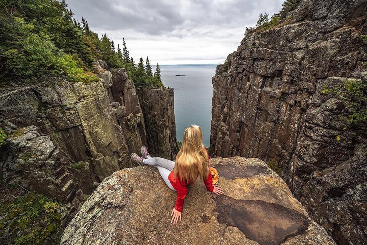 Young woman sitting on a rock at top of Sleeping Giant. 
