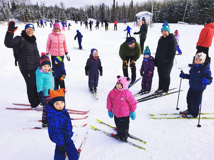 Group of children and adults on skis standing in a circle. 