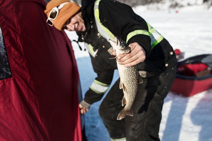 Woman holding a fish - ice fishing.