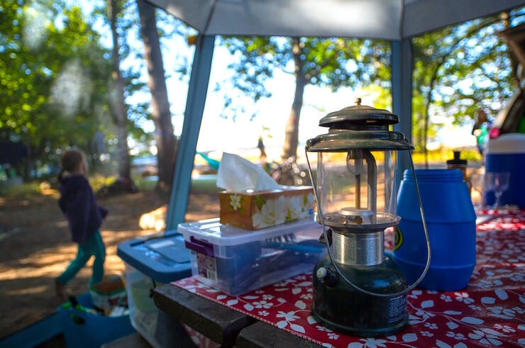 Coleman lantern and other camping gear on a picnic table. 