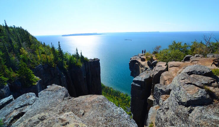 Two people standing on rock cliff overlooking Lake Superior
