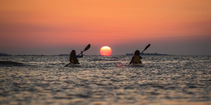 two people kayaking at sunset