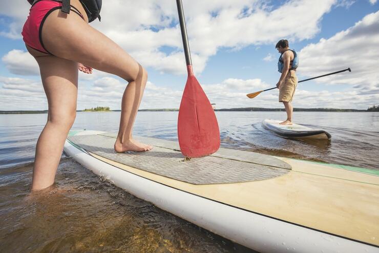 Woman stepping on paddleboard in shallow water