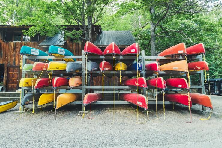 many canoes on a large outdoor canoe rack at an outfitter