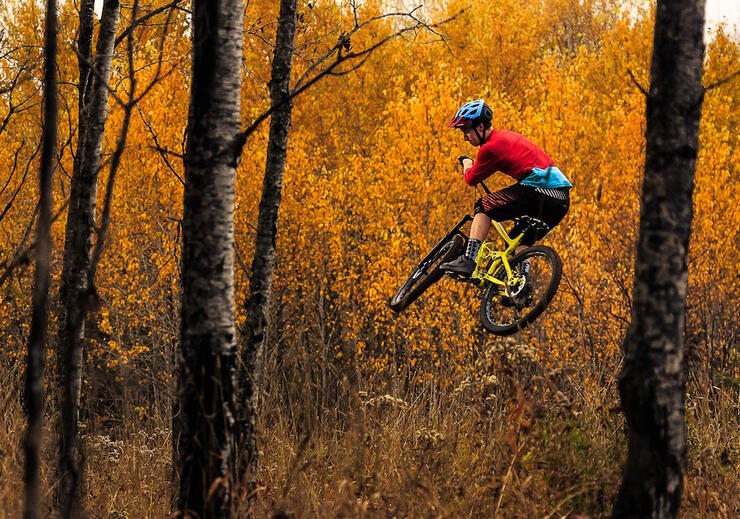 Man on mountain bike catching air in fall forest 
