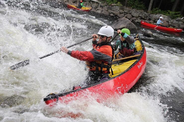Man paddling a canoe in extreme whitewater. 