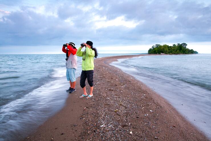 Two people with binoculars standing on narrow sand point