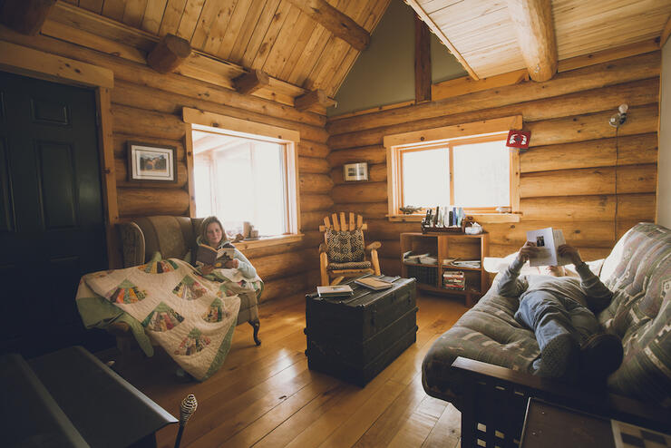 Woman and man relaxing in a cozy log cabin. 