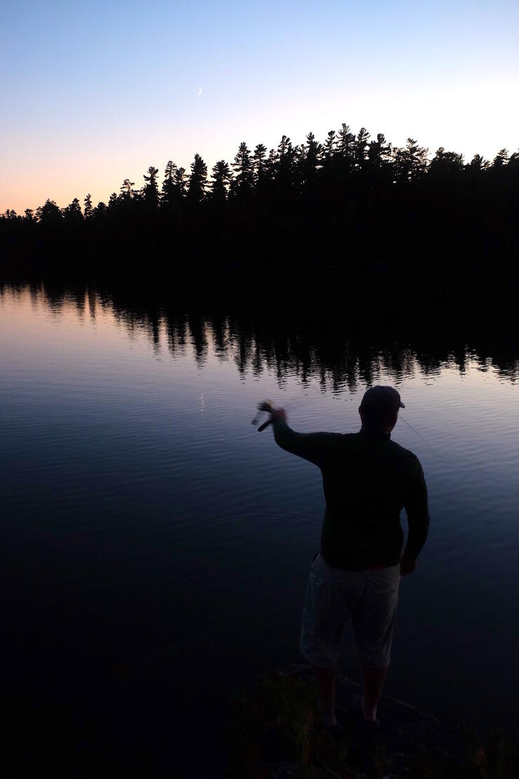 Man fishing during the twilight hours.