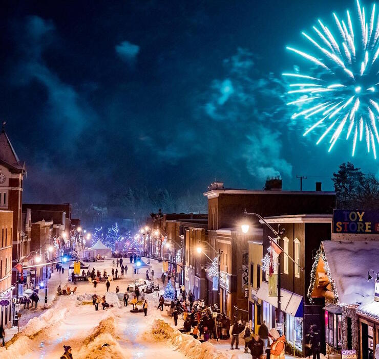 View of people tubing down Bracebridge main street surrounded by historic building.
