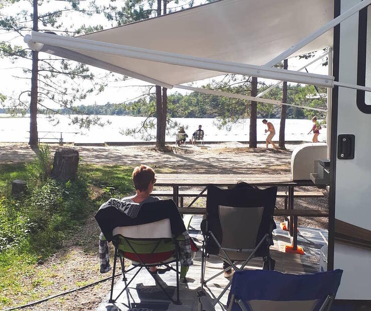 Man sitting in a camp chair looking out to a beach.