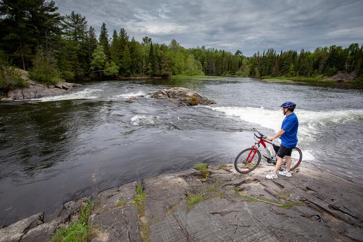 Cyclist standing beside bike beside a beautiful river 