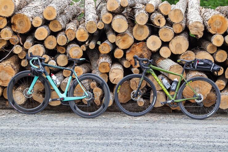 Two bikes leaning against a wood pile