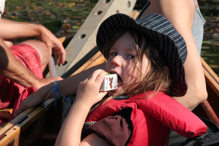 Young girl eating a box of raisins.