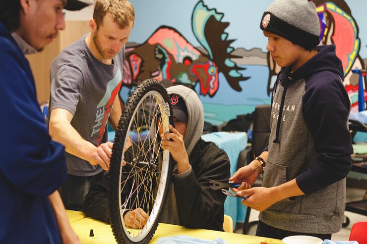Young men fixing a bicycle tire on a table. 